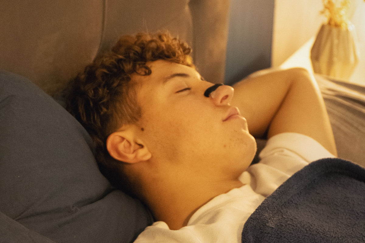 Ung mand sover i varmt lys med O² PRO-næseudvider