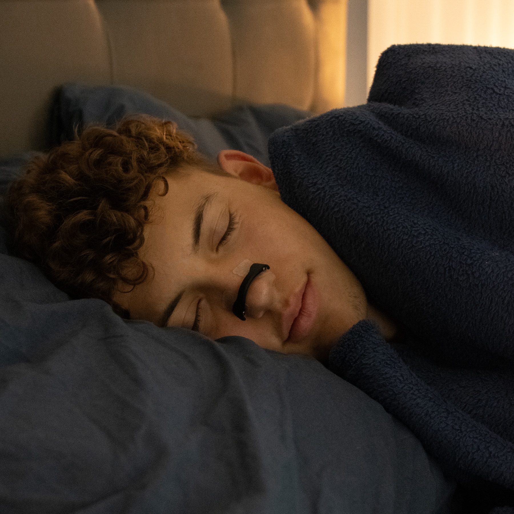 En person der sover på siden med sort næsebånd på